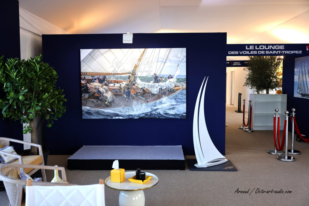 Sculpture d'art nautique OCTO Art Audio exposée dans le Lounge des Voiles de Saint-Tropez avec photo de voilier classique.