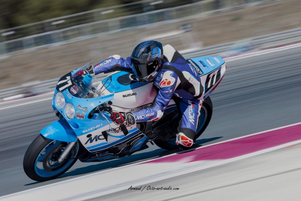 Photo de sport moto montrant une Suzuki GSX-R de course bleue et blanche, numéro 77, inclinée en virage sur le circuit Paul Ricard durant le Bol d'Or Classic 2025.