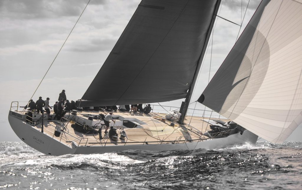 Photographie de profil du Maxi Yacht Galateia naviguant sous voile, mettant en valeur son pont épuré et l'envergure de son mât de carbone lors d'une régate de prestige.