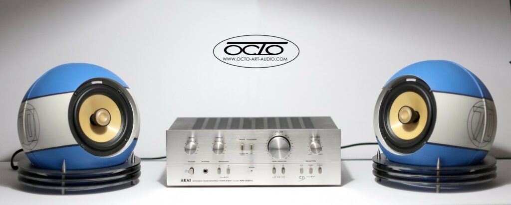 Système haute-fidélité composé d'un amplificateur stéréo Akai centré entre deux enceintes sphériques Octo 300 Édition Racing.