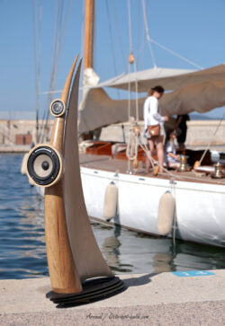 Inspiration marine : l'enceinte de la série "Les Voiles" d'Octo Art Audio en escale sur le port de Saint-Tropez. Enceinte design Octo Art Audio issue de la série "Les Voiles", sculptée en bois et installée sur le port de Saint-Tropez devant un voilier classique, illustrant l'inspiration nautique de la marque.