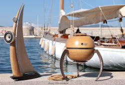 L'harmonie marine : les modèles Octo 1200 et Octo 800 en escale sur le port de Saint-Tropez. Enceintes design Octo 1200 (série Les Voiles) et Octo 800 exposées sur le port de Saint-Tropez, devant un voilier traditionnel, symbolisant l'union entre art acoustique et univers nautique par Octo Art Audio.