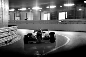 L'ombre et la lumière dans le tunnel mythique de Monaco : une Formule 1 historique saisie dans l'esthétique intemporelle du noir et blanc. Photographie en noir et blanc d'une monoplace historique pilotant dans le célèbre tunnel du circuit de Monaco, capturée avec une ambiance dramatique par Arnaud d'Octo Art Audio.