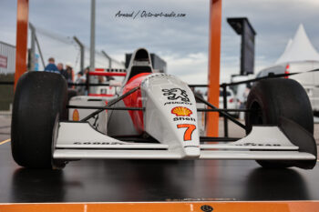 Immersion sur le paddock : photographie de détail d'une monoplace de légende, symbole de l'histoire du sport automobile. Vue frontale d'une monoplace historique de Formule 1 portant les logos Peugeot, Shell et le numéro 7, photographiée lors d'un événement au circuit Paul Ricard par Arnaud.