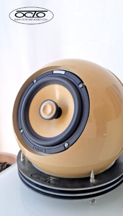 Vue verticale de l'enceinte artisanale OCTO 300, mettant en valeur son design sculptural et son système de découplage mécanique sur pointes. Enceinte acoustique sphérique OCTO 300 par Octo Art Audio, finition beige laquée avec haut-parleur Focal et socle en acier gravé sur pointes de découplage.