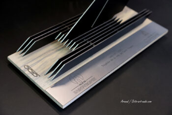 Vue géométrique et lignes fuyantes du Trophée de la Ville de Saint-Tropez, mettant en valeur le travail du bois et du métal signé Octo Art Audio. Vue en perspective du Trophée officiel SailGP de la Ville de Saint-Tropez, associant métal noir, plaque brossée et socle en bois gravé OCTO.