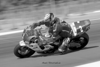L'écurie JEM Racing et sa monture numéro 2 immortalisées en noir et blanc sur le Circuit Paul Ricard. Photographie artistique en noir et blanc d'une moto classique de course numéro 2 du team JEM Racing en plein filé au Bol d'Or Classic.