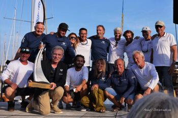 Célébration de la victoire et présentation du trophée perpétuel de l'Hyères Europa Cup (classe 12mJI). Équipage vainqueur sur le podium de l'Hyères Europa Cup tenant le trophée en acier et bois sculpté par Octo Art Audio.
