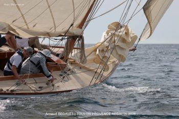 Esterel (8mJI) : une glisse intemporelle sous le soleil de la Méditerranée. Détail de l'étrave du voilier classique Esterel (8mJI) naviguant sur une mer scintillante lors de la Toulon Provence Regatta 2026.