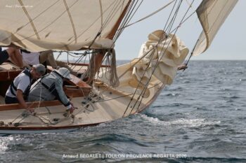 Esterel (8mJI) : une glisse intemporelle sous le soleil de la Méditerranée. Détail de l'étrave du voilier classique Esterel (8mJI) naviguant sur une mer scintillante lors de la Toulon Provence Regatta 2026.