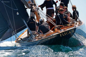 Flica II (K-14): Timeless elegance and mahogany reflections in the Mediterranean. Close-up of the stern of the 12mR yacht Flica II (K-14) with golden lettering, crew in action during the Toulon Provence Regatta 2026.