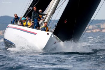 Vitesse et technique : Un équipage au rappel sous des voiles en composite noir technique. Vue rapprochée d'un yacht de course 12mJI South Australia en composite en pleine gîte, équipage au rappel et voiles en carbone noires, lors de la Toulon Provence Regatta 2026.