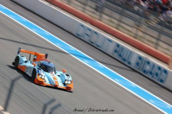 Plein gaz sur le Mistral : la Ginetta-Nissan LMP2 Gulf (n°28) au Castellet. Prototype Ginetta-Nissan LMP2 livrée Gulf passant à haute vitesse sur la ligne droite du Mistral au Paul Ricard. Action shot of the Ginetta-Nissan LMP2 Gulf racing at high speed on the Mistral straight, Circuit Paul Ricard.