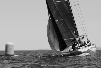 Force et contrastes en mer. Le 12mJI en composite New Zealand (KZ-7) en pleine manœuvre à la bouée lors des régates de l'Europa Cup 2026. Tirage d'art disponible en édition limitée. Photographie d'art en noir et blanc du voilier classique 12mJI New Zealand KZ-7 virant à côté d'une bouée de régate Toulon Provence Méditerranée lors de l'Europa Cup 2026 à Hyères.