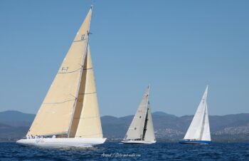 Trio de légende en baie de Hyères. Les mythiques 12mJI French Kiss (F-12), South Australia (KA-8) et France 1 s'affrontent sur fond de reliefs varois lors de l'Europa Cup 2026. Tirage d'art disponible en édition limitée. Photographie en plan large de trois voiliers classiques 12mJI, dont French Kiss F-12, South Australia KA-8 et France 1, naviguant de profil lors de l'Europa Cup 2026 à Hyères.