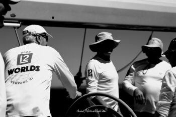 Le regard du skipper. Le légendaire Marc Pajot aux commandes du 12mJI French Kiss (F-12) en pleine concentration avec son équipage lors de l'Europa Cup 2026. Tirage d'art disponible en édition limitée. Photographie d'art en noir et blanc de Marc Pajot à la barre du voilier classique 12mJI French Kiss F-12, entouré de son équipage lors de l'Europa Cup 2026 à Hyères.