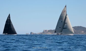 Confrontation aux Îles d'Or. Les mythiques 12mJI South Australia (KA-8) et New Zealand (KZ-7) croisent devant la pointe du Crocodile à Porquerolles. Tirage d'art disponible en édition limitée. Photographie de course au large montrant le duel entre les voiliers 12mJI South Australia KA-8 et New Zealand KZ-7 devant le rocher du Crocodile à Porquerolles lors de l'Europa Cup 2026.