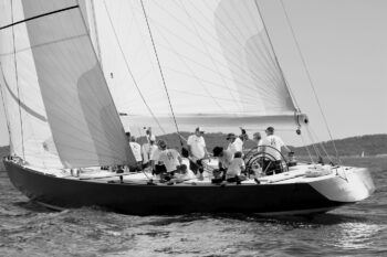 Lignes intemporelles et contrastes profonds. Le légendaire 12mJI France 1 capturé en noir et blanc à la relance dans la baie de Hyères lors de l'Europa Cup 2026. Tirage d'art disponible en édition limitée. Photographie artistique en noir et blanc du voilier de tradition 12mJI France 1 naviguant de trois-quarts arrière lors de l'Europa Cup 2026 à Hyères. Vue sur l'équipage en action dans le cockpit et les lignes de la coque sur fond de relief côtier.